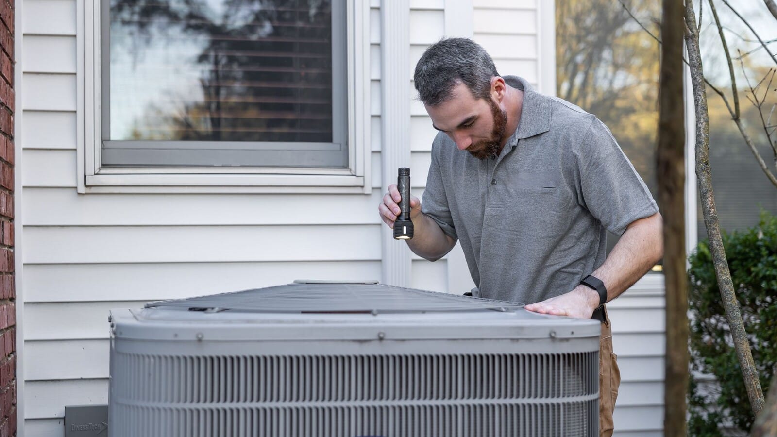 Technician inspecting an outdoor HVAC unit as part of preventive maintenance