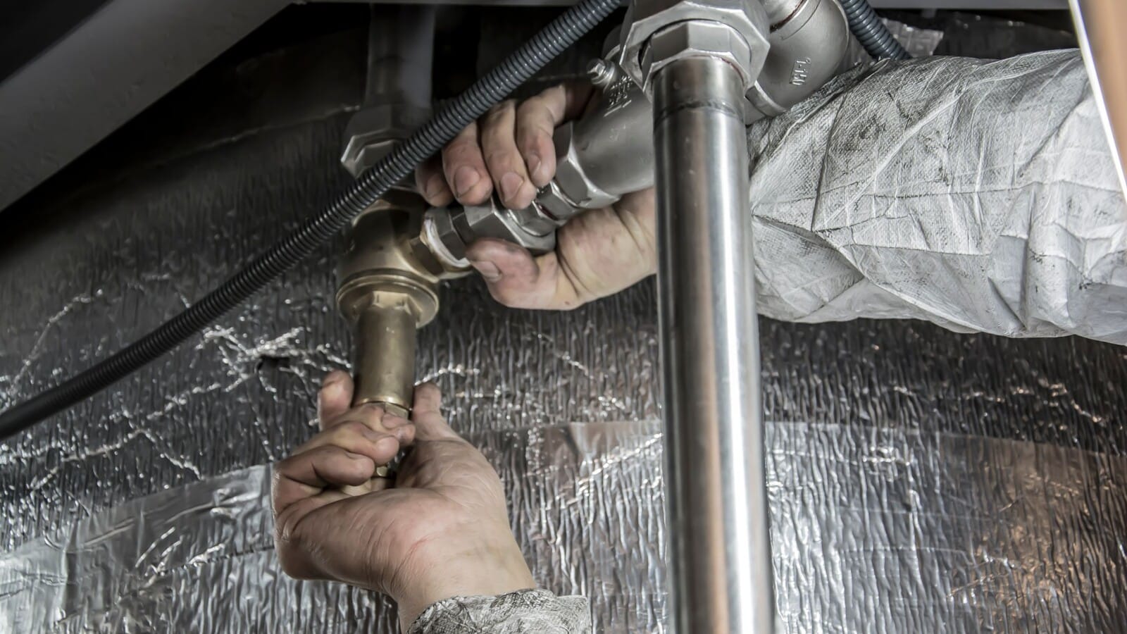 Plumber servicing building pipes during scheduled maintenance